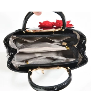 Interior view of black patent leather tote bag showing multi-compartment lining and gold zippers