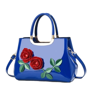 Blue patent leather tote bag with elegant 3D red rose detail and gold hardware accents