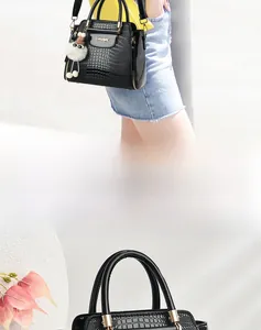 Dettaglio della borsa shopping nera coccodrillo con logo dorato e ciondolo di peluche