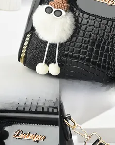 Dettaglio macro della pelle nera a coccodrillo con logo dorato e catena in metallo