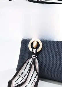 Détail d'un foulard en soie et pendentif ambre sur un sac à main bleu tressé élégant