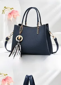 Détail d'un sac à main bleu foncé texturé avec poignées et pendentif foulard soyeux