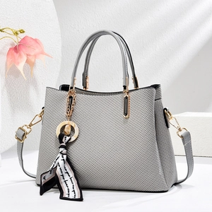 Sac à main gris texturé avec foulard en soie sur support géométrique et fond floral épuré