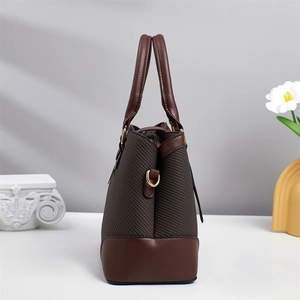 Detail view of brown pebbled leather and woven texture with gold D-ring on a tote bag