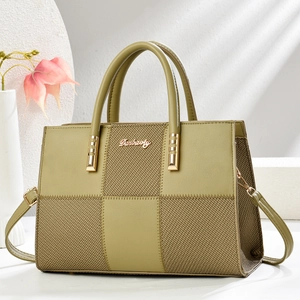 Detail of olive green handbag featuring textured woven fabric and gold brand logo plate