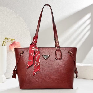 Detail of burgundy textured leather tote bag with elegant silk scarf on handle