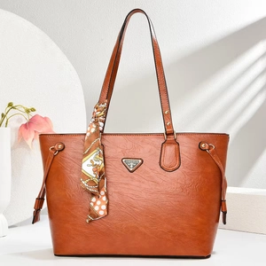 Vintage brown leather tote bag with elegant silk scarf handle and metal logo plaque