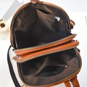 Close-up of brown backpack interior with multiple compartments and gold zipper details