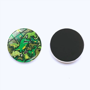 Close-up of 25mm cartoon dinosaur glass fridge magnet showing glossy front and magnetic back