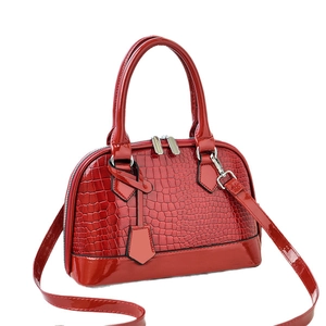 Glossy red crocodile embossed shell bag with top handles and adjustable strap