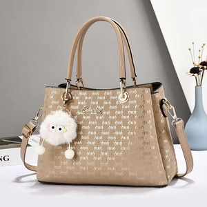 Détail du sac cabas beige avec motif UIUI, logo en métal et charm en peluche en situation