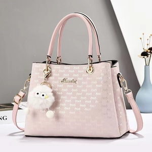Détail d'un cabas rose avec imprimés logo, finitions dorées et breloque œil en peluche
