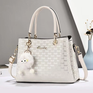 Détail d'un sac cabas blanc avec logo doré métallique et breloque en peluche