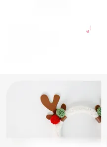 Close-up of reindeer antler headband with festive red green pom-poms and leather details