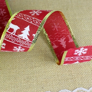 Close-up of red Christmas ribbon with gold wavy edges and white snowflake reindeer prints