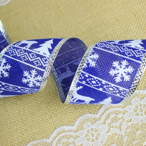 Macro shot of royal blue Christmas ribbon featuring white reindeer and snowflake motifs