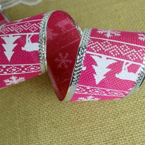 Detail of rose red faux linen Christmas ribbon with white reindeer and snowflake prints