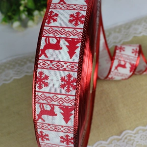 Close-up of white linen Christmas ribbon with red reindeer, snowflake and tree patterns