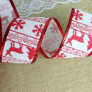 Detail of Christmas ribbon with red reindeer and tree patterns on rustic burlap