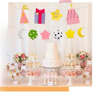Dettaglio del festone di compleanno in feltro con stelle e torta sopra un tavolo decorato