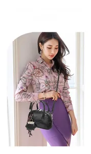 Détail du sac Boston noir en similicuir avec un charm chat et un pompon sur le côté