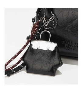 Vue détaillée d'un charm de mini sac en cuir huilé noir avec une chaîne en métal argenté