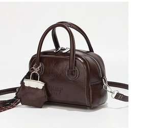 Détail d'un sac vintage marron foncé en cuir ciré avec coutures blanches contrastées et boucle