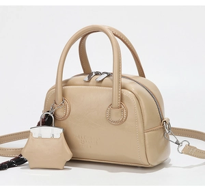Détail du mini sac Boston beige avec fermetures argentées et breloque assortie
