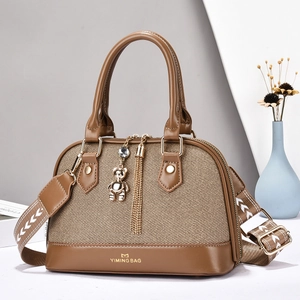 Sac à main marron tressé avec bandoulière large et pendentif ours doré élégant