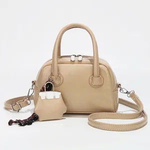 Sac à main Boston beige élégant avec finition brillante, poignées et mini breloque