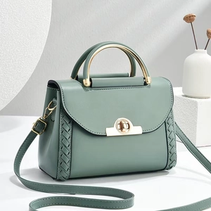 Sac bandoulière en cuir vert sauge avec poignée dorée et détails tissés sur le côté