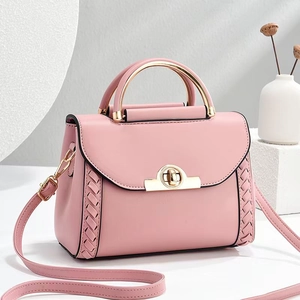 Détail du sac bandoulière rose avec poignée dorée circulaire et accents tissés
