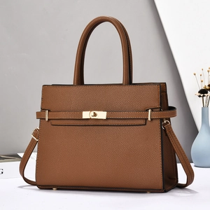 Detail view of the brown lychee grain leather handbag featuring gold twist-lock closure
