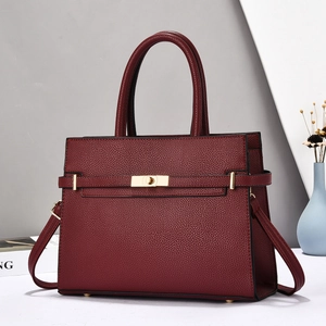 Detail of burgundy pebble leather handbag featuring golden twist lock and sturdy handles