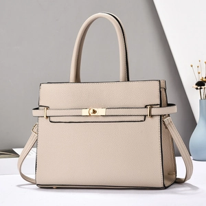 Detail of lychee pattern leather handbag featuring a light gold twist lock and strap