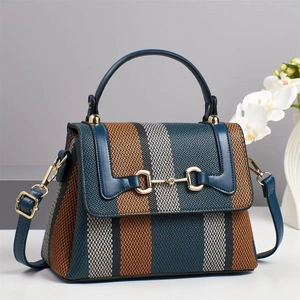 Detail of color-block striped canvas handbag with blue leather flap and gold horsebit buckle
