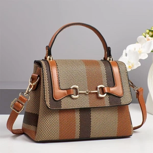 Detail of color-block striped woven bag showing brown leather handle and gold horsebit buckle