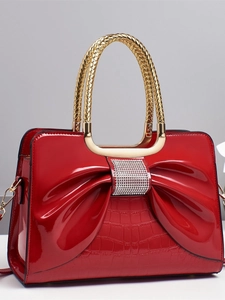 Sac à main en cuir verni rouge avec nœud diamanté, poignée dorée et texture croco