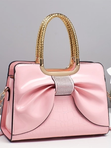 Sac à main en cuir verni rose avec nœud et détails en strass, vue studio de face