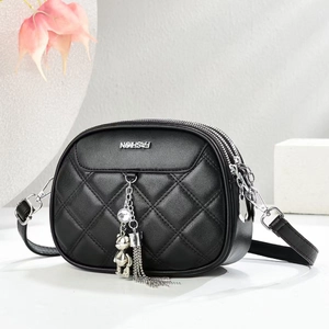 Close-up of black quilted crossbody bag with silver hardware and bear charm detail