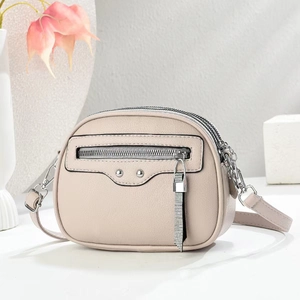 Detail of light beige crossbody bag with lychee texture and silver rivet hardware decor