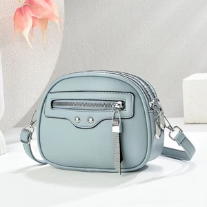 Detail view of light blue crossbody bag with lychee texture and triple zipper layers