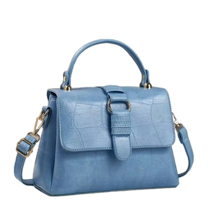 Light blue faux crocodile skin handbag with top handle and gold hardware on white background
