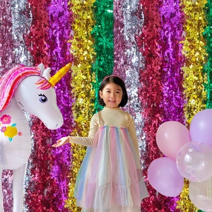 Close-up of colorful foil fringe curtains and unicorn balloon party background décor