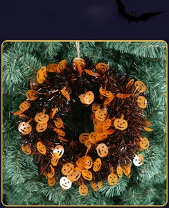 Detail of Halloween pumpkin wreath with orange sequins and black tinsel on green backdrop