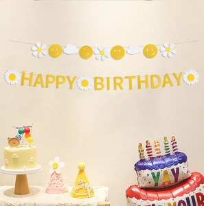 Detail of felt daisy birthday banner with yellow letters hung above a party cake