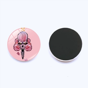 Detail of 25mm round glass skull magnet with pink background and black magnetic back