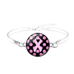 Detalle de pulsera plateada con lazo rosa y colgante de cristal para el cáncer de mama