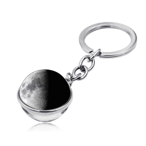 Close-up of crescent moon glass ball pendant with polished silver keychain and shadow