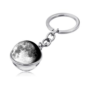 Close-up of double-sided glass moon ball pendant on silver metal keychain ring